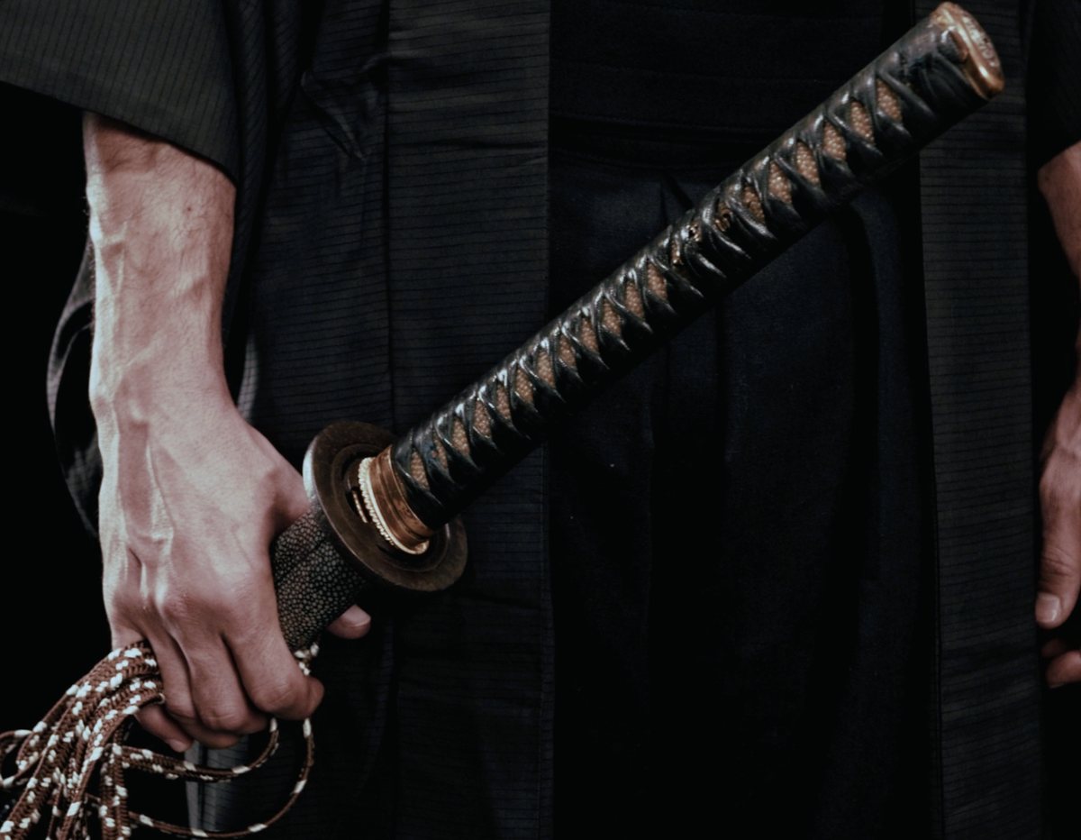 Mà subjectant l'empunyadura d'una katana, amb el cordó (sageo) penjant