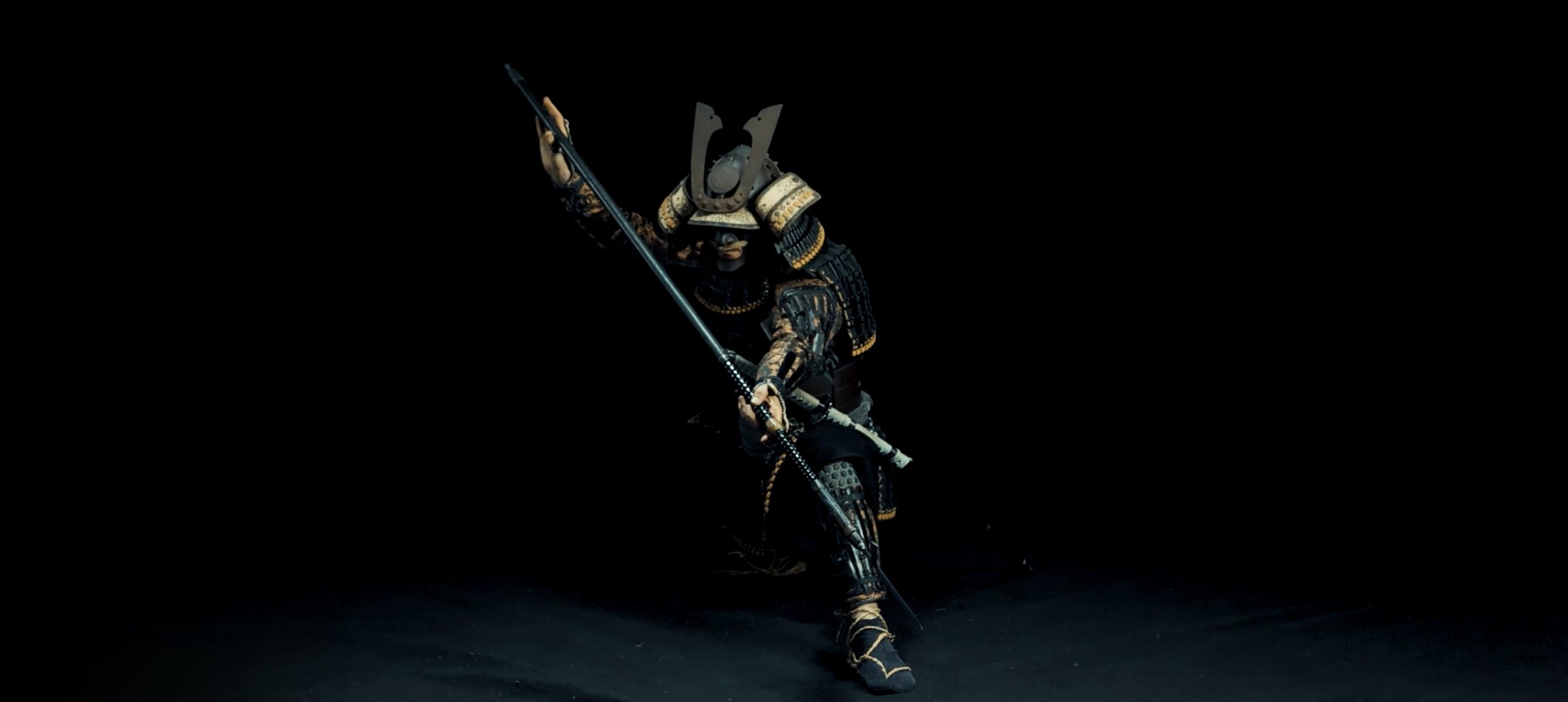 Practicant amb armadura samurai completa i un katakama yari, sobre fons negre